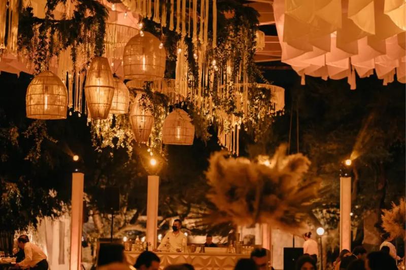 Lámparas de mimbre y telas suspendidas sobre una recepción de noche