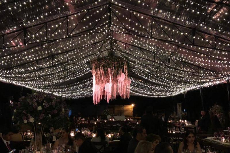 Carpa forrada de luces con un arreglo de flores suspendido al centro